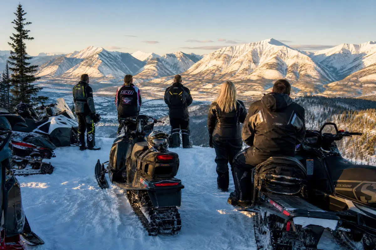 A group of snowmobile riders gathered on a snowy trail